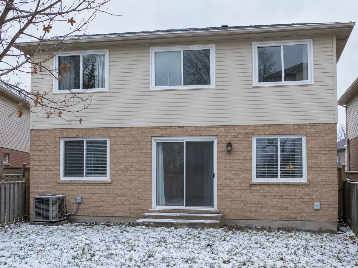 Back of a 1980s brick house in early winter with one upstairs pane fogged between the glass